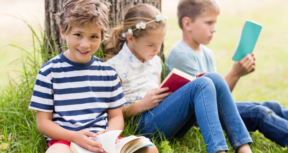 Dzieci uczą się czytać siedząć pod drzewem