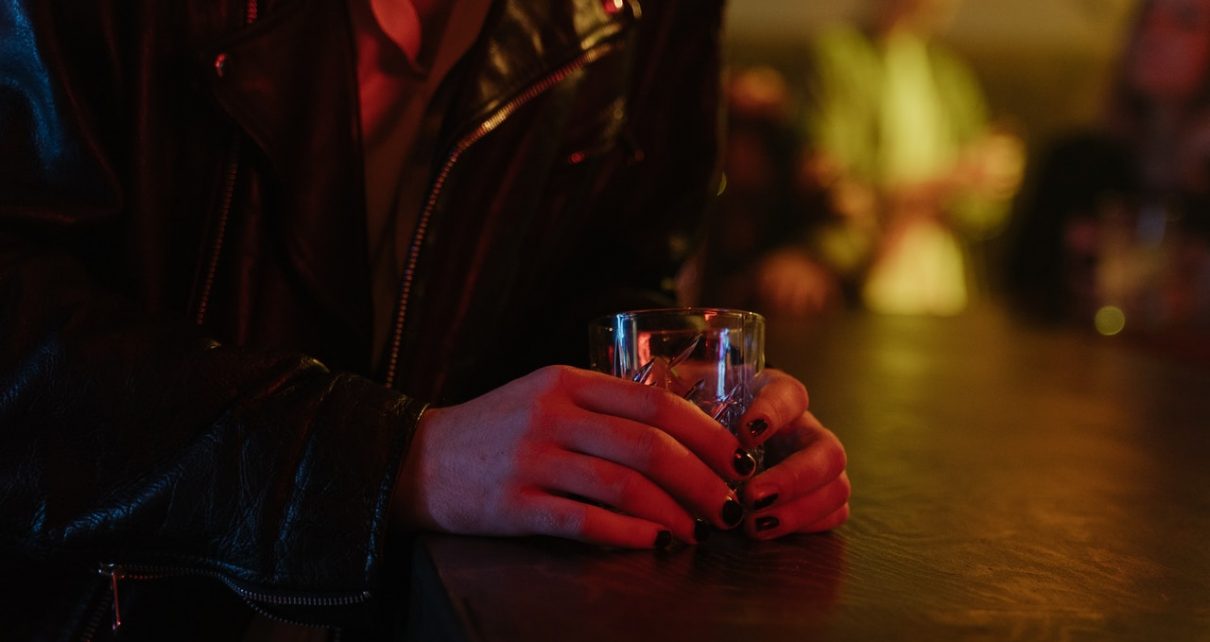 Kobieta trzyma w dłoniach szklanke z alkoholem
