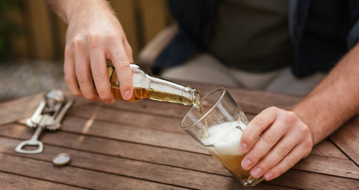 Mężczyzna mający problem z alkoholem wlewa piwo do szklanki
