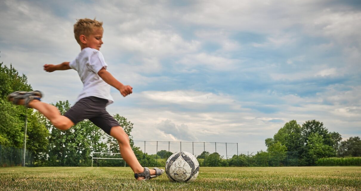 Chłopiec gra na boisku w piłkę nożną