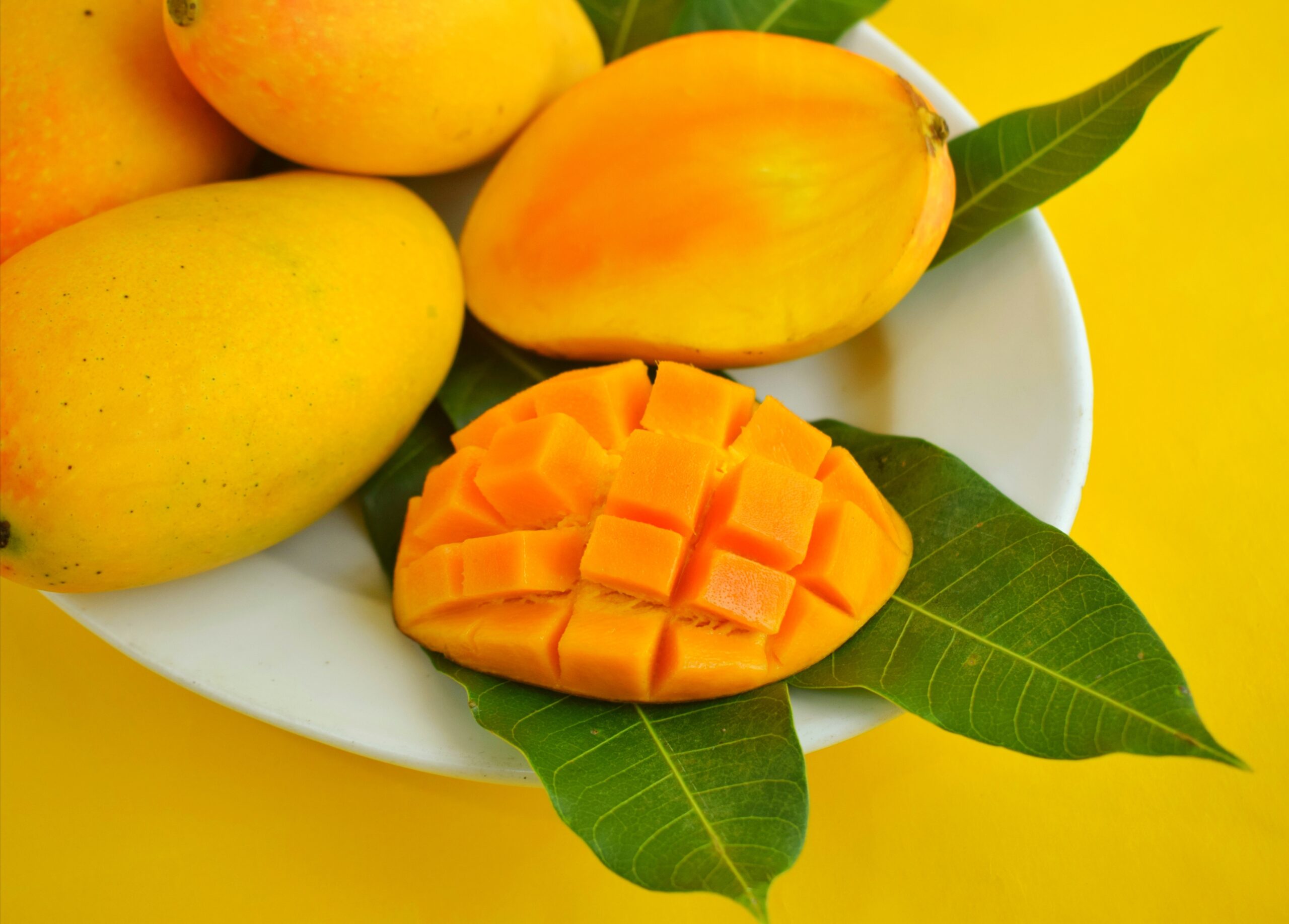 Obrane i nie obrane mango na talerzu na żółtym tle