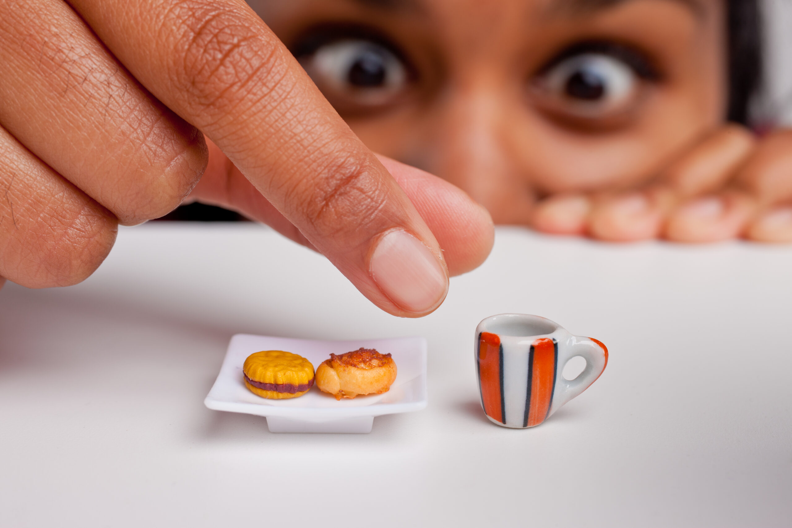 Kobieta z miniaturkami jedzenia i picia na stoliku, co symbolizuje dietę NFZ
