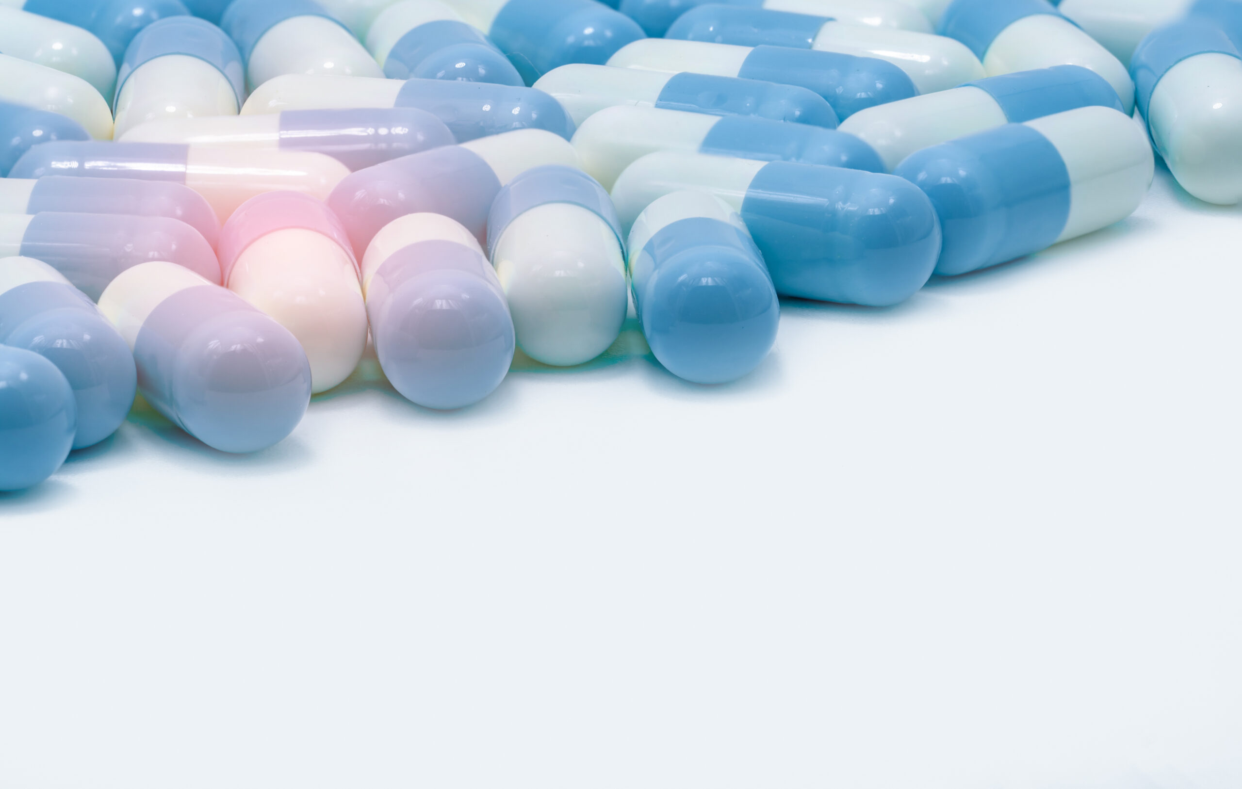 Na czystym białym tle rozlokowane są niebieskie tabletki wykorzystywane w medycynie naturalnej. Ich jasny odcień odzwierciedla czystość i naturalność, podkreślając ich związek z holistycznym podejściem do zdrowia i dobrostanu.