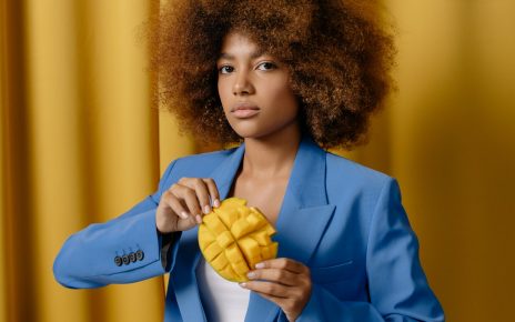 Kobieta w niebieskim żakiecie trzymająca w dłoniach ponacinane mango