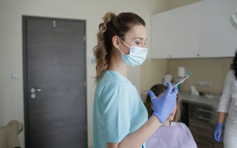 Dentystka trzyma w dłoni strzykawke ze znieczuleniem stomatologicznym