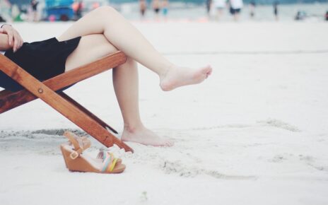 Kobieta z wyleczona ostrogą pietową siedzi na plaży bez butów