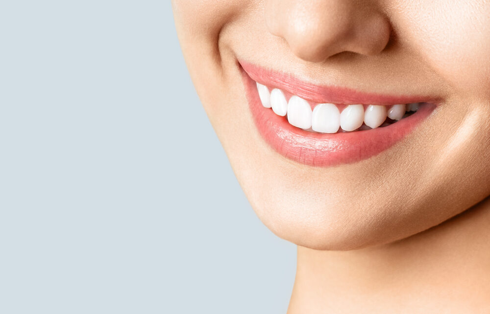 Kobieta z białymi zębami używa wybielającej pasty do zębów