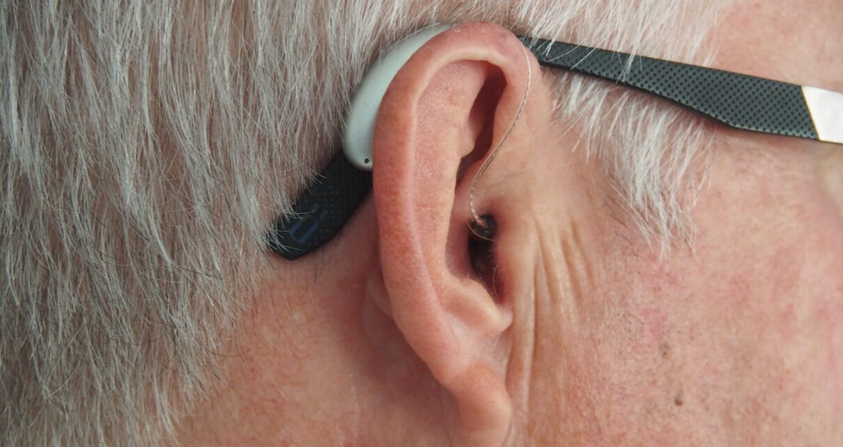 Mężczyzna ma na uchu aparat słuchowy