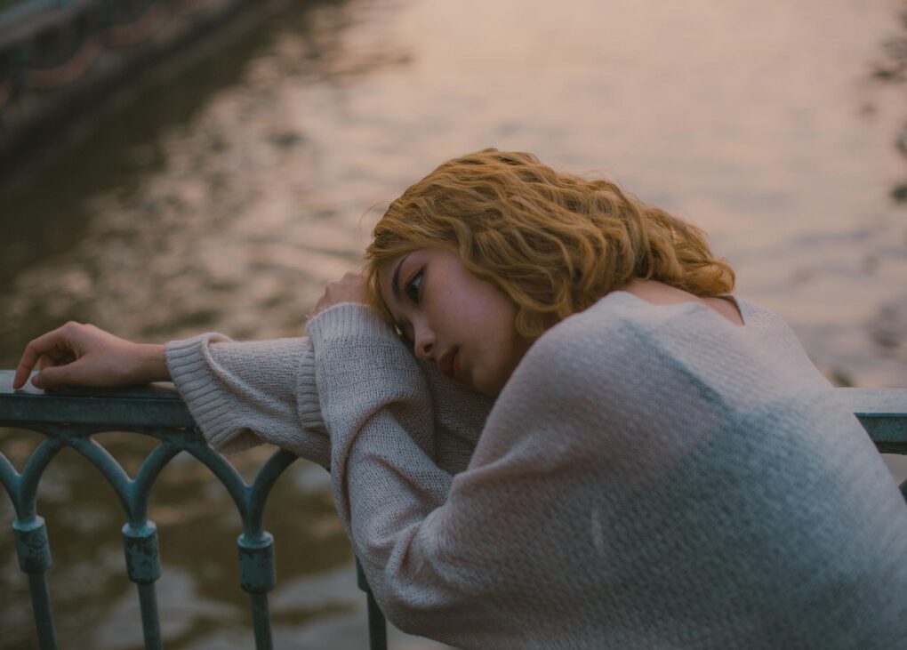 Dziewczyna z depresją oparta o most nad rzeką