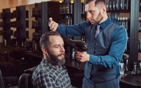 Fryzjer układa mężczyźnie modną fryzure męską