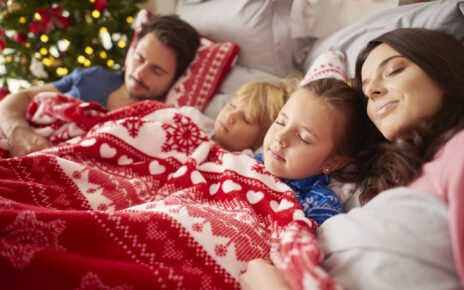 Cała rodzina śpi na łóżku pod świąteczną pościelą