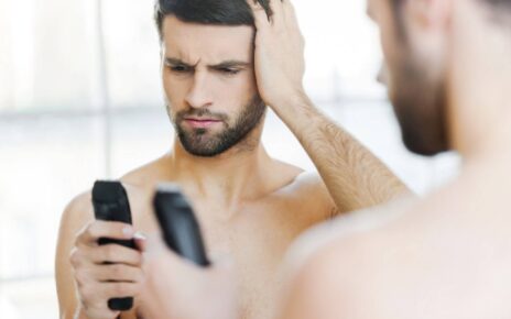 Mężczyzna w łazience przed lustrem korzysta z maszynki do golenia