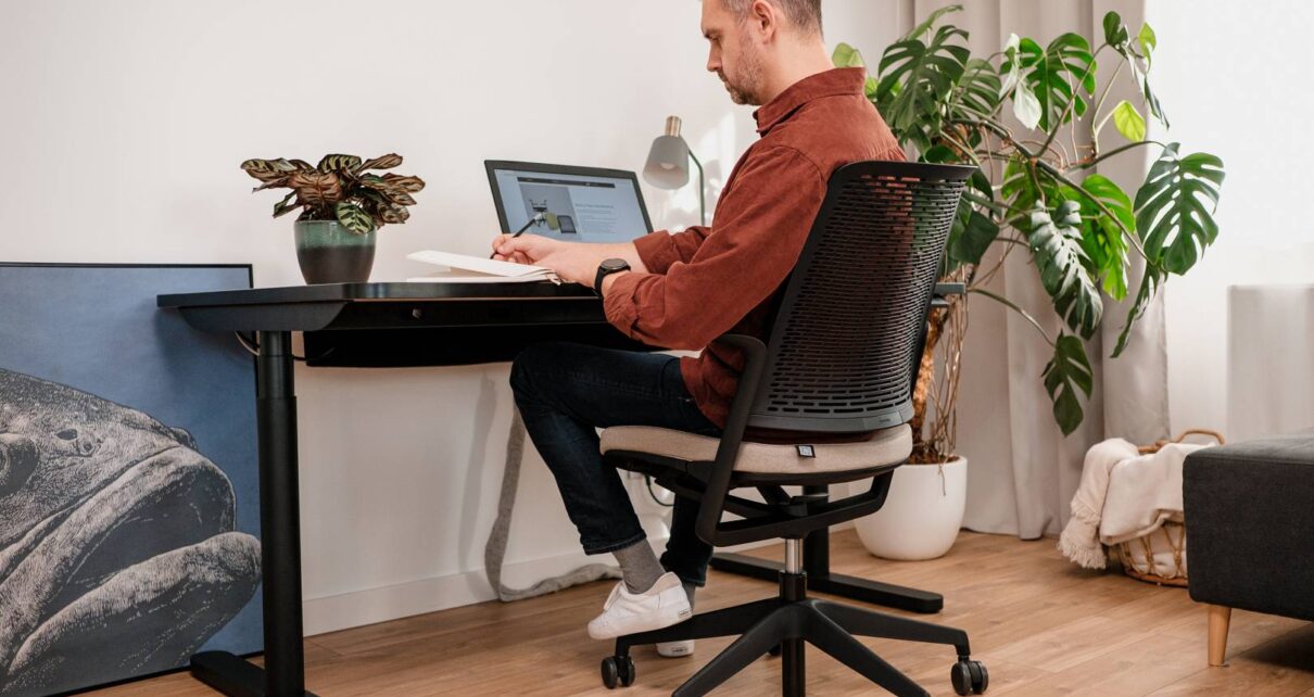 Mężczyzna siedzi na wygodnym krześle obrotowym przy biurku