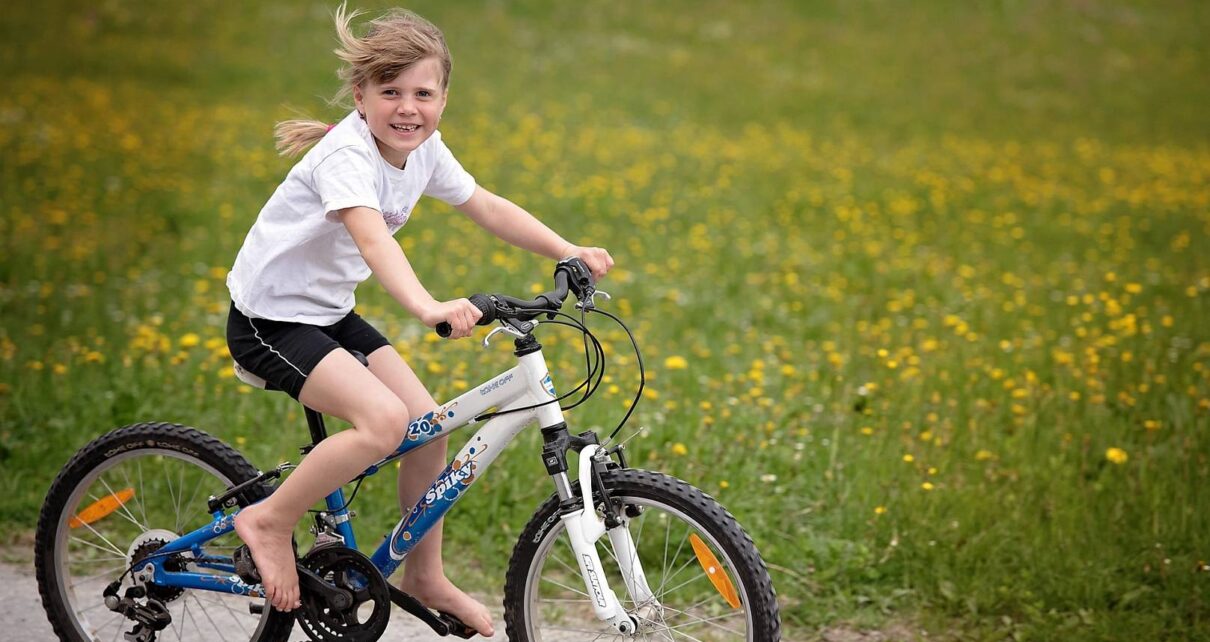 Dziewczynka jeździ na swoim rowerze obok łąki