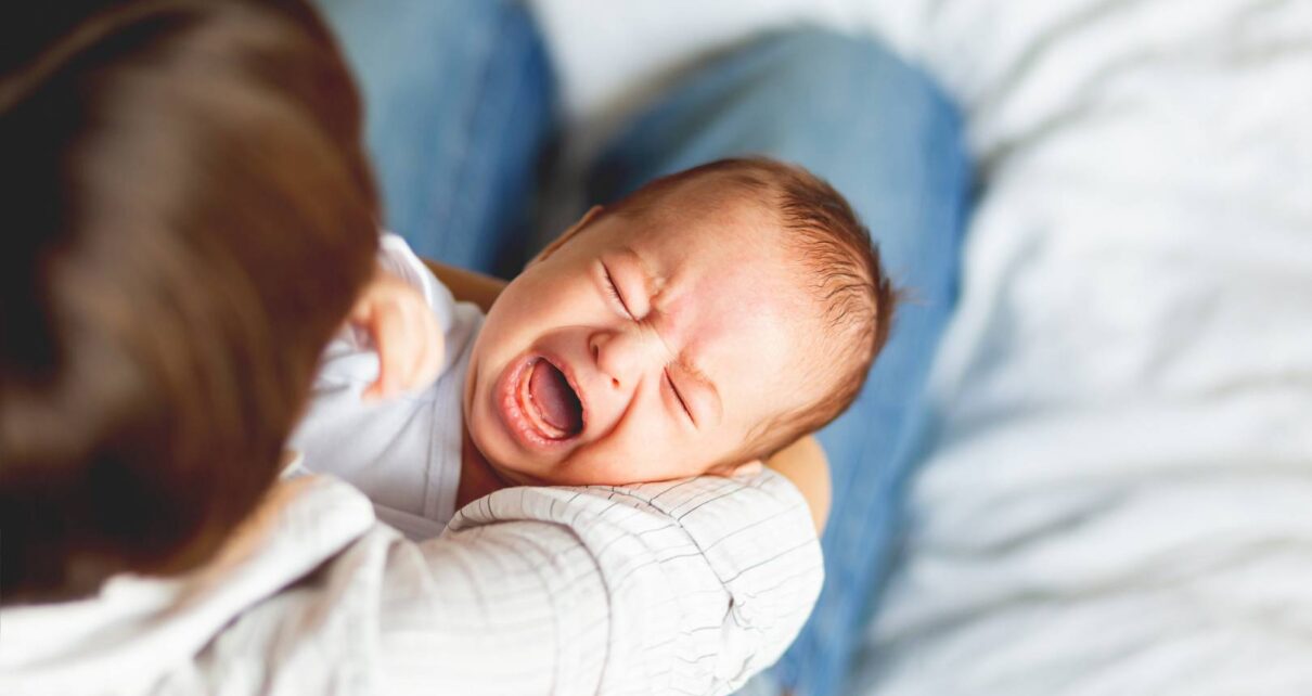 Kobieta próbuje uspokoić niemowlę które ma kolke