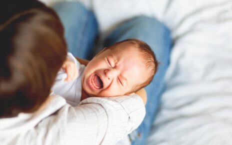 Kobieta próbuje uspokoić niemowlę które ma kolke