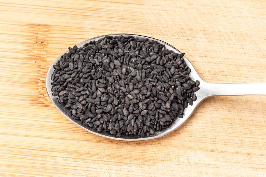 Nasiona czarnego sezamu leżą na łyżce w kuchni