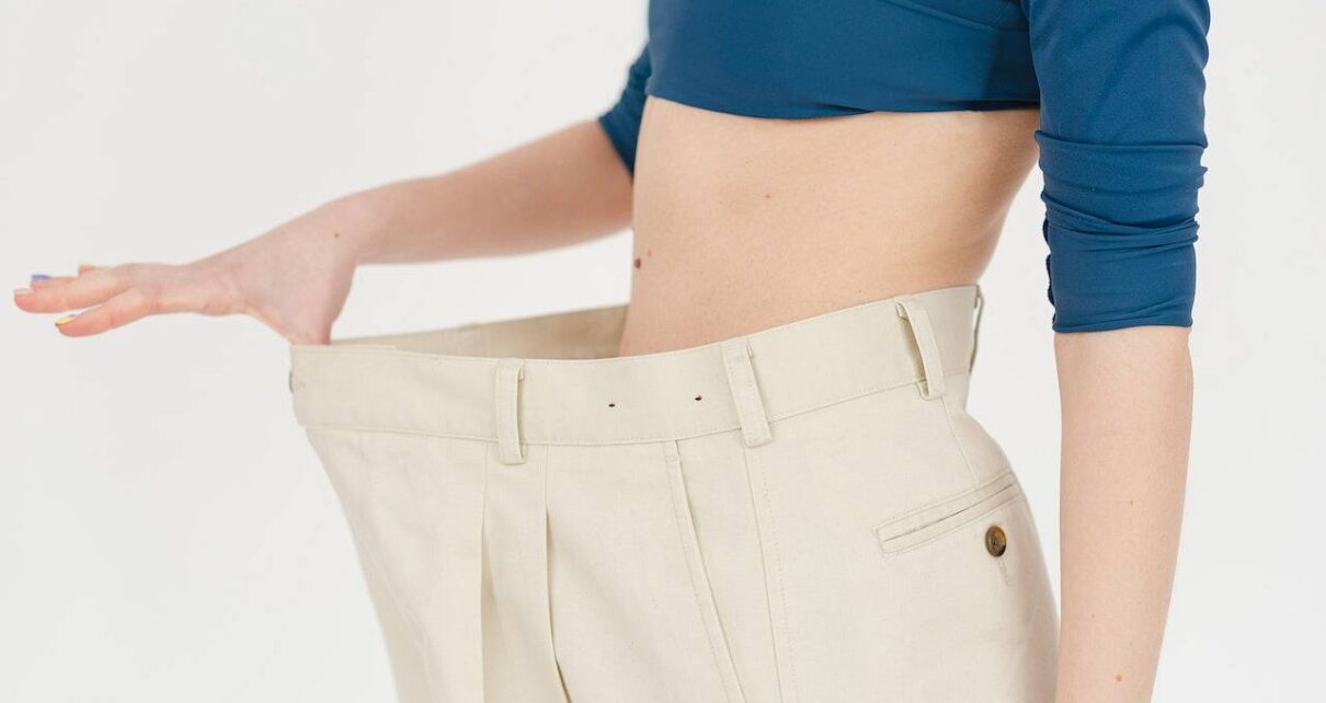 Kobieta na diecie zakłada swoje stare, za duże spodnie