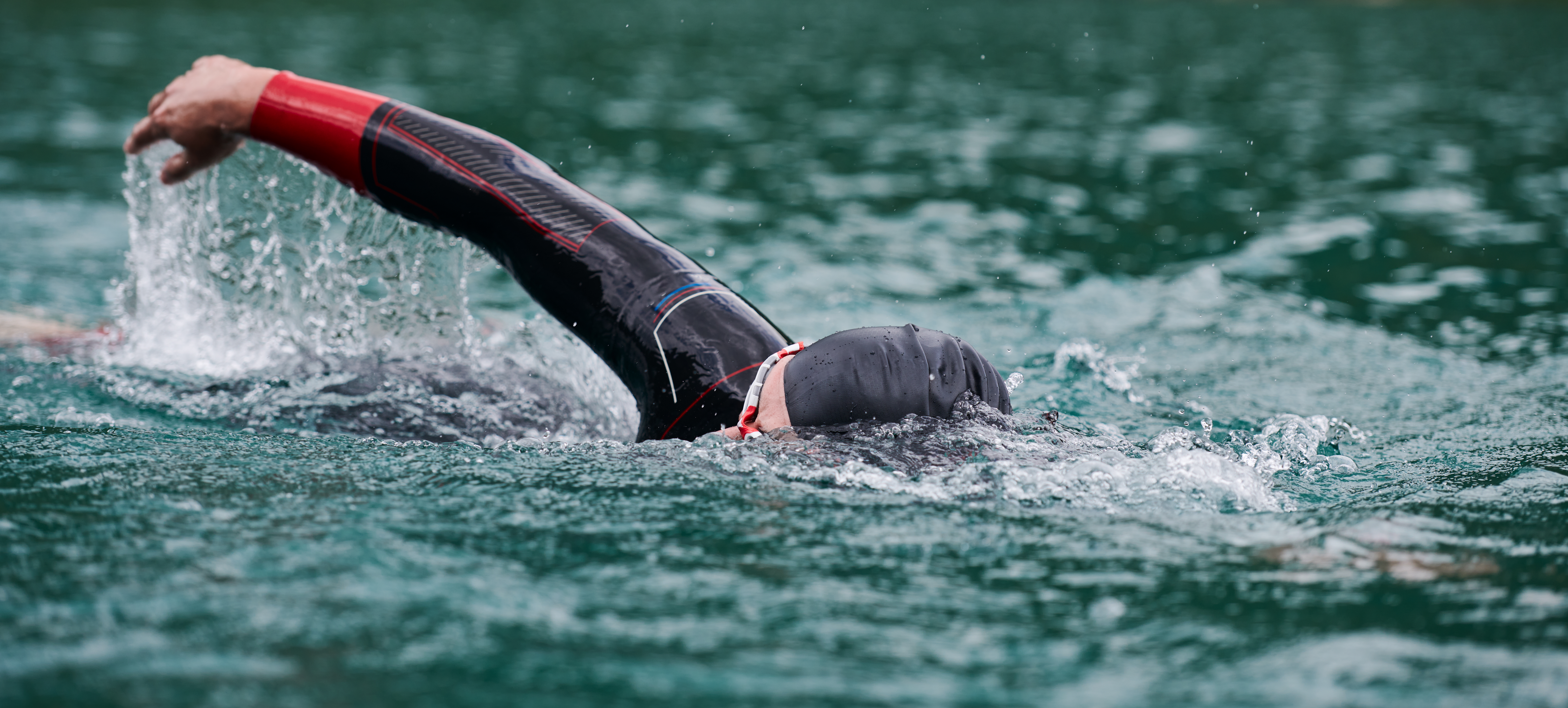 Na tym ekscytującym obrazku możemy zobaczyć mężczyznę w pełnym skupieniu, pływającego przez turkusowe wody podczas zawodów triathlonowych. Jego determinacja i siła są widoczne w każdym ruchu, podkreślając nie tylko wyzwanie, jakim jest trójboje, ale także piękno poświęcenia w dążeniu do osiągnięcia celu.