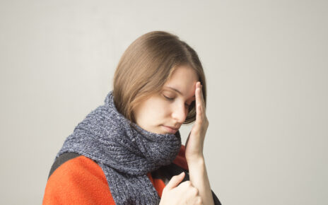 Na zdjęciu widoczna jest kobieta, która wyraźnie odczuwa bóle mięśni związane z przeziębieniem. Kobieta jest osłabiona, ma zaczerwienione oczy i zaciskane usta, co sugeruje, że przeżywa silny dyskomfort związany z chorobą. Obrazek taki może stanowić przypomnienie, jak ważne jest dbanie o zdrowie w okresie jesienno-zimowym i jakie konsekwencje może mieć zaniedbanie w tej kwestii