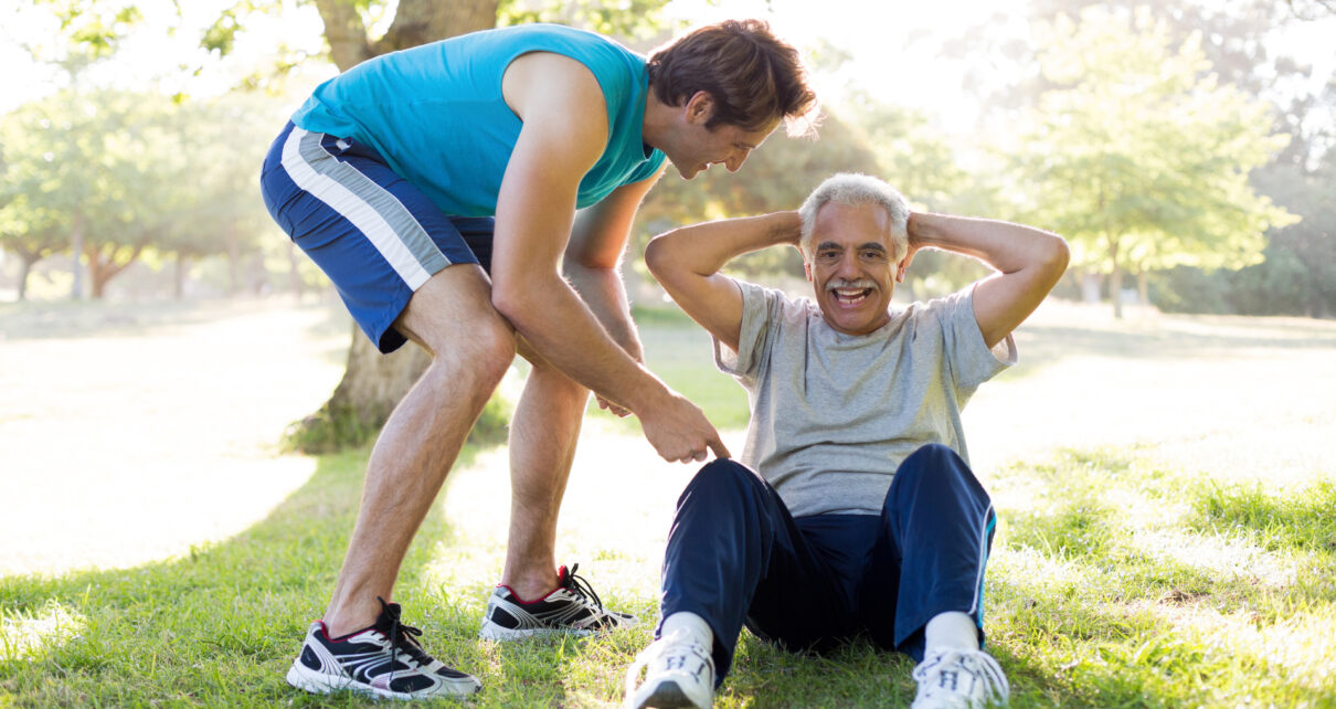 Na obrazku widoczny jest starszy mężczyzna, który ćwiczy na świeżym powietrzu. Senior wykonuje ćwiczenia rozciągające i wzmacniające mięśnie, co widać po jego postawie i wyrazie twarzy. W tle widać drzewa i zieloną trawę, co wskazuje na to, że senior ćwiczy na łonie natury. Aktywność fizyczna jest bardzo ważna dla zdrowia seniorów, ponieważ pozwala zachować sprawność i dobre samopoczucie na długość życia. Obrazek stanowi przypomnienie o konieczności regularnego ruchu oraz o tym, jak ważne jest dbanie o zdrowie w starszym wieku.
