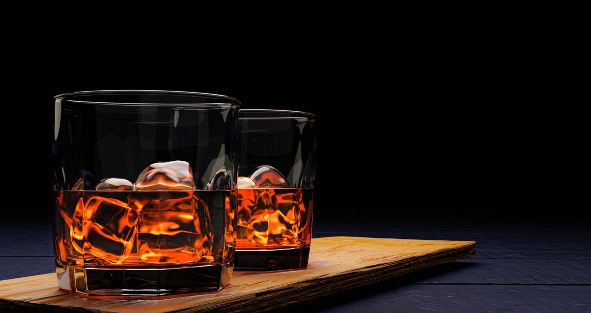Na tym kuszącym obrazku widzimy dwie szklanki, wypełnione alkoholem i lodem, tworzące harmonijną kompozycję. Kryształowe kostki lodu delikatnie unoszą się w płynie, dodając elegancji i orzeźwienia. Refleksy światła na powierzchni szkła podkreślają apetyczny wygląd tego drinka, zapraszając do chwili relaksu i przyjemności