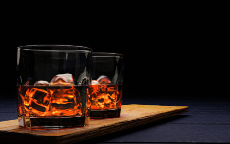 Na tym kuszącym obrazku widzimy dwie szklanki, wypełnione alkoholem i lodem, tworzące harmonijną kompozycję. Kryształowe kostki lodu delikatnie unoszą się w płynie, dodając elegancji i orzeźwienia. Refleksy światła na powierzchni szkła podkreślają apetyczny wygląd tego drinka, zapraszając do chwili relaksu i przyjemności
