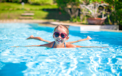 Na tym ujmującym obrazku widzimy uśmiechniętą dziewczynkę, która cieszy się latem, pływając w basenie. Jej radość jest zarazem inspiracją i przypomnieniem, jak ważne jest uprawianie sportów w okresie letnim. Zanurzenie się w wodzie to doskonały sposób na ochłodę, aktywność fizyczną i radosną zabawę podczas gorących dni