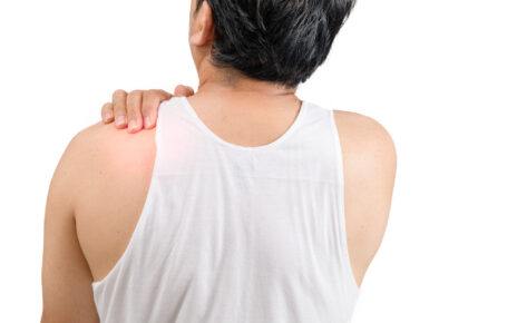 Mężczyzna z bólem pleców na wysokości łopatek trzymający się za ramię