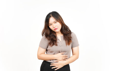 Kobieta, która trzyma się za brzuch z widocznym wyrazem zaniepokojenia, spowodowanym bulgotaniem w brzuchu