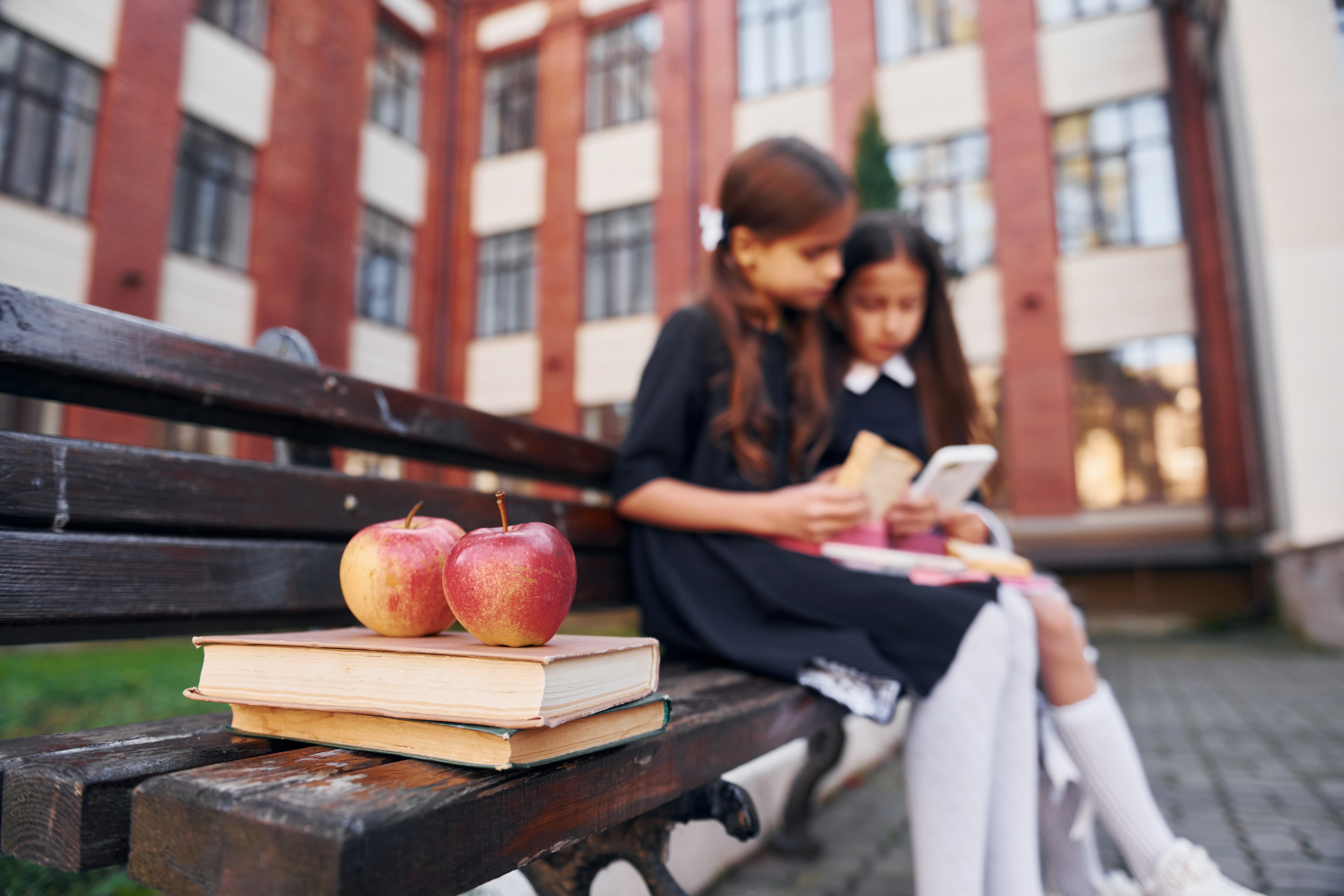 Dziewczynki czytające lekturę na szkolnym podwórku